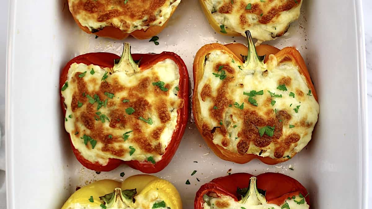 Spinach Artichoke Stuffed Peppers in white casserole with chopped parsley on top