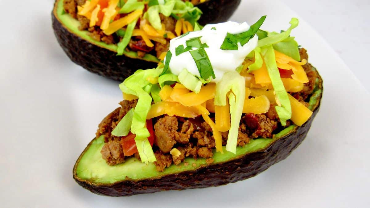 Taco Stuffed Avocados with lettuce, sour cream and cilantro on top