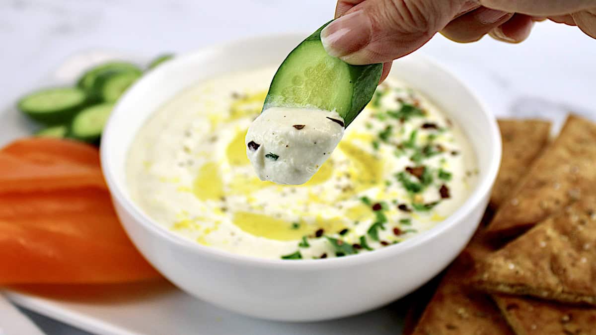 Whipped Feta Dip with cucumber being dipped in it