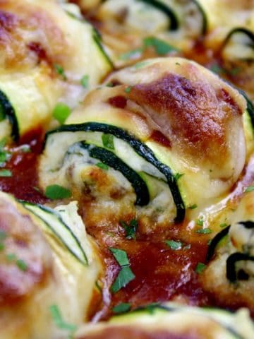 closeup of Zucchini Rollatini in casserole dish with marinara sauce