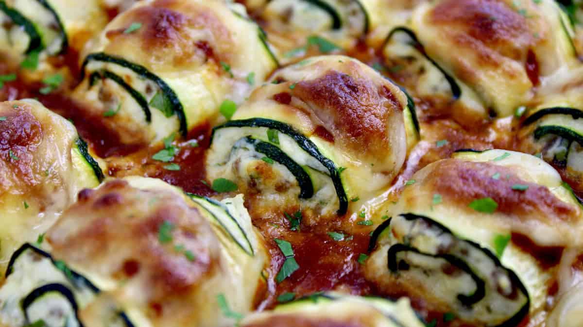 closeup of Zucchini Rollatini in casserole dish with marinara sauce