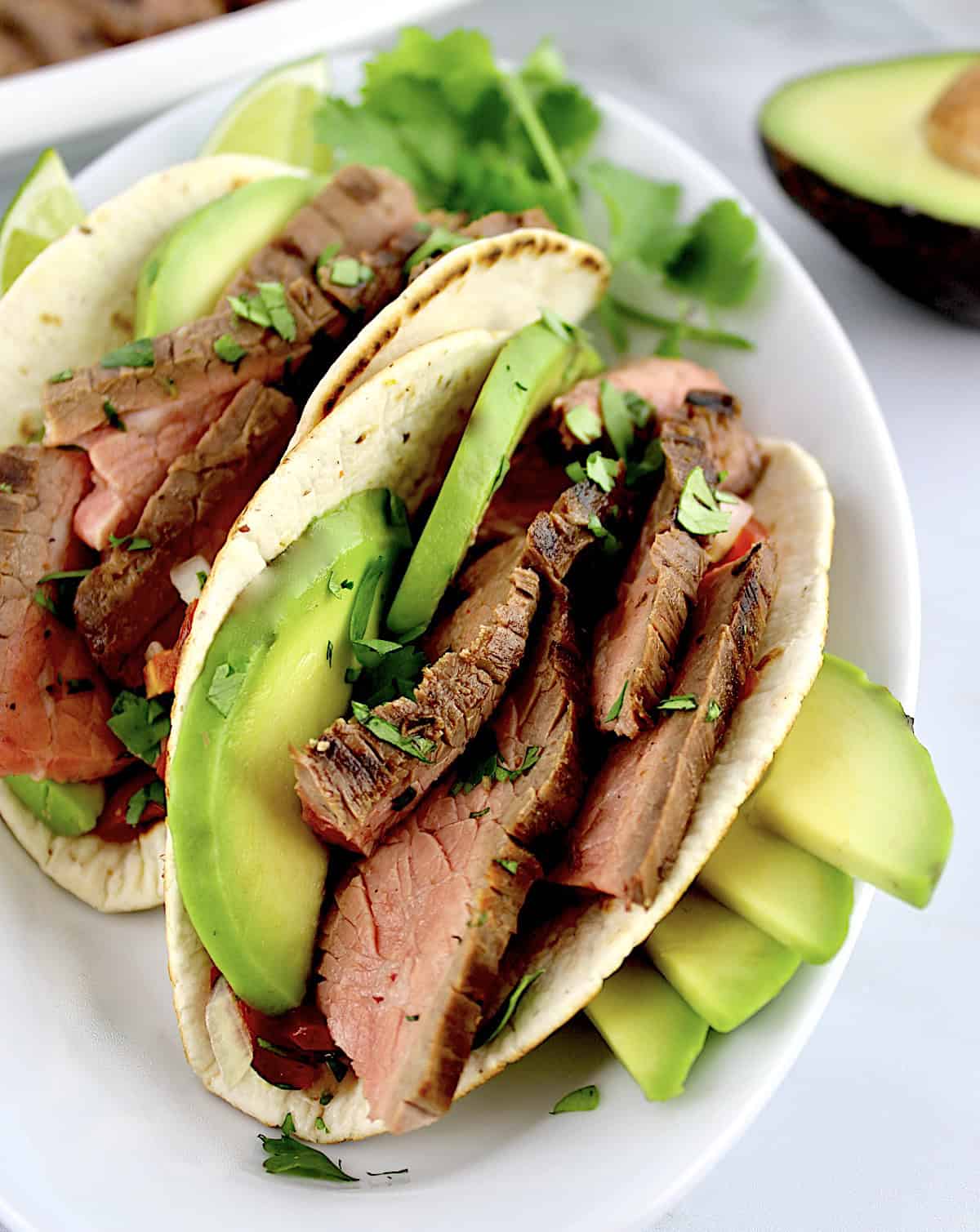 Carne Asada in 2 tacoes with avocado slices
