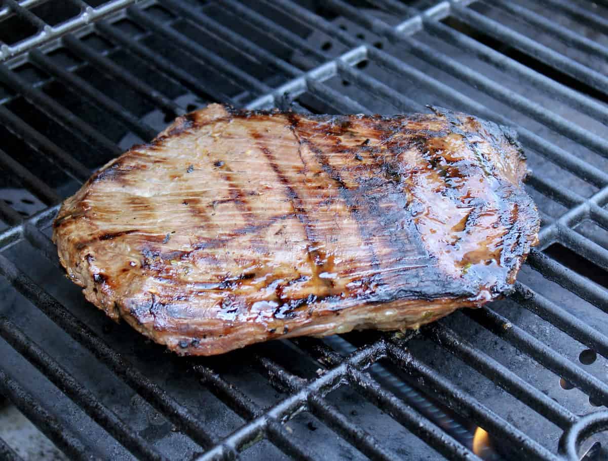 flank steak cooking on grill