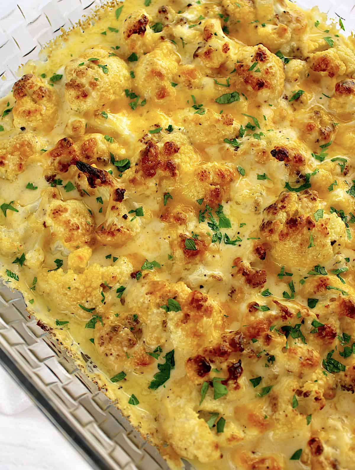 Cheddar Roasted Cauliflower in glass casserole with chopped parsley