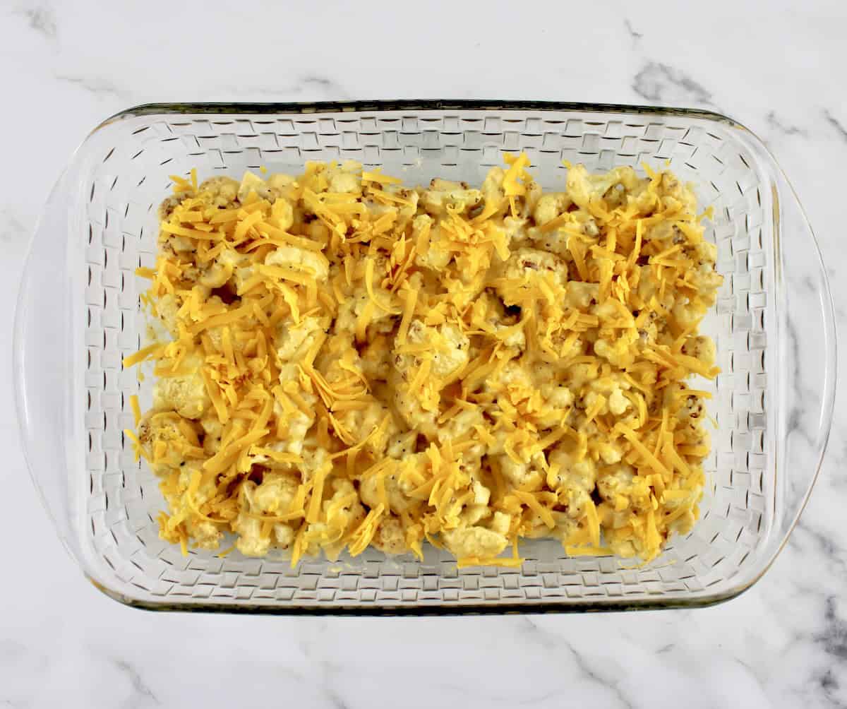 Cheddar Roasted Cauliflower with shredded cheddar on top in glass baking dish