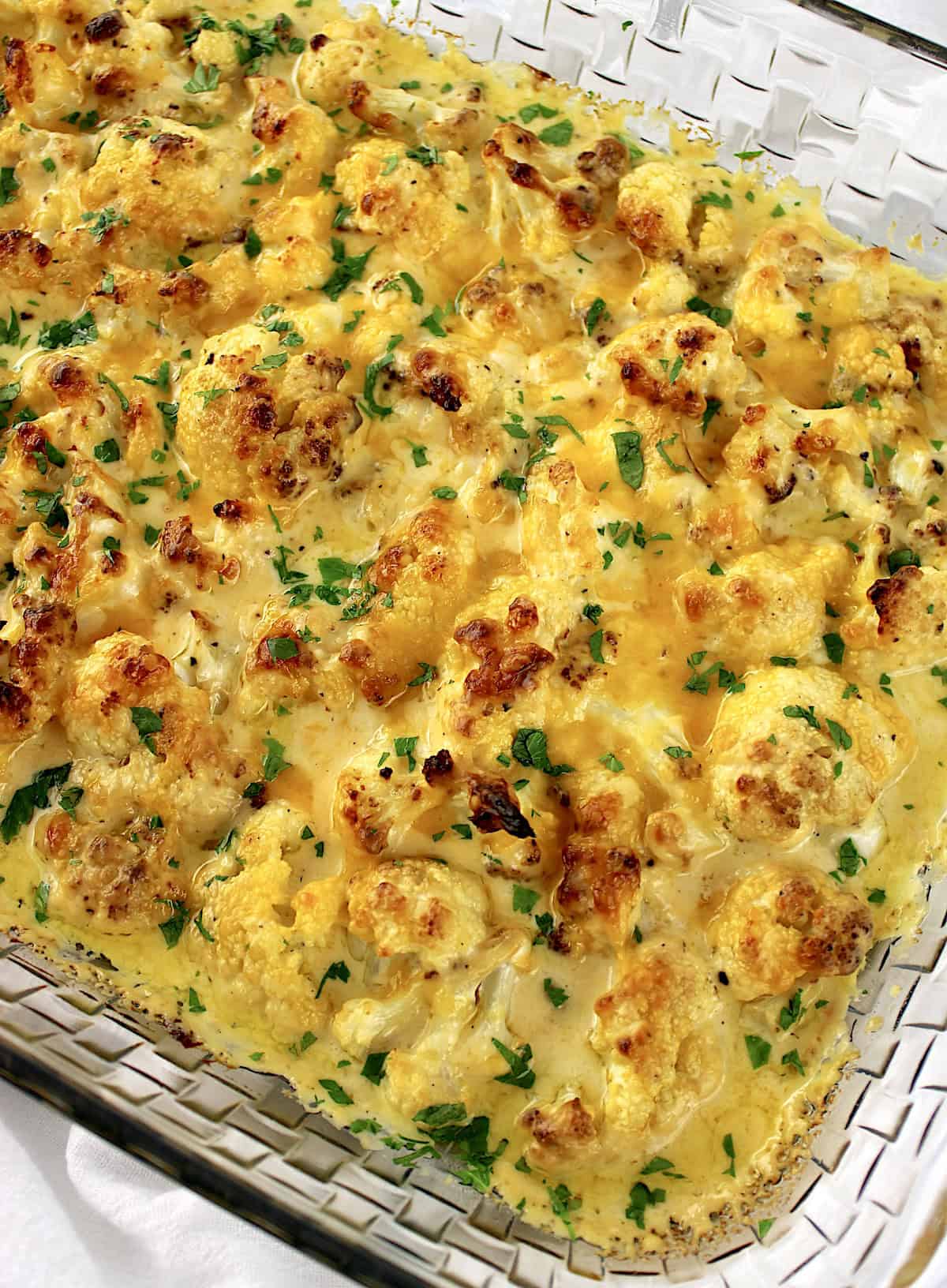 Cheddar Roasted Cauliflower in glass casserole with chopped parsley