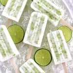 overhead view of 6 Coconut Lime Popsicles on ice with lime slices