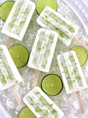 overhead view of 6 Coconut Lime Popsicles on ice with lime slices