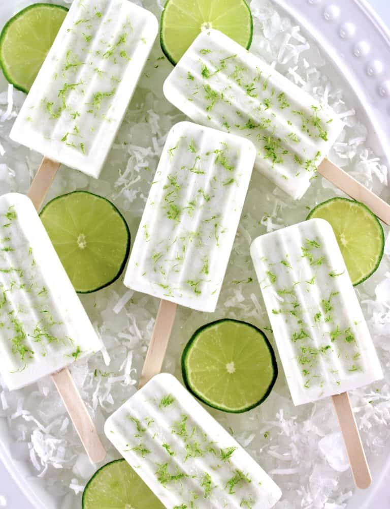 overhead view of 6 Coconut Lime Popsicles on ice with lime slices