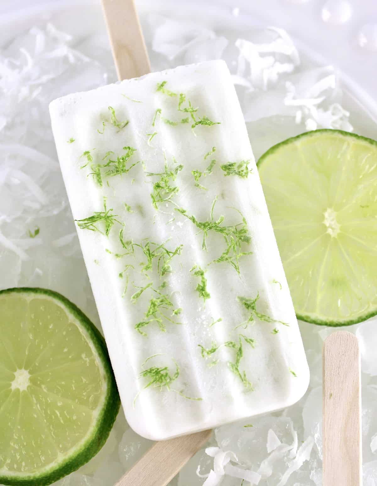 overhead view of Coconut Lime Popsicle on ice with 2 lime slices