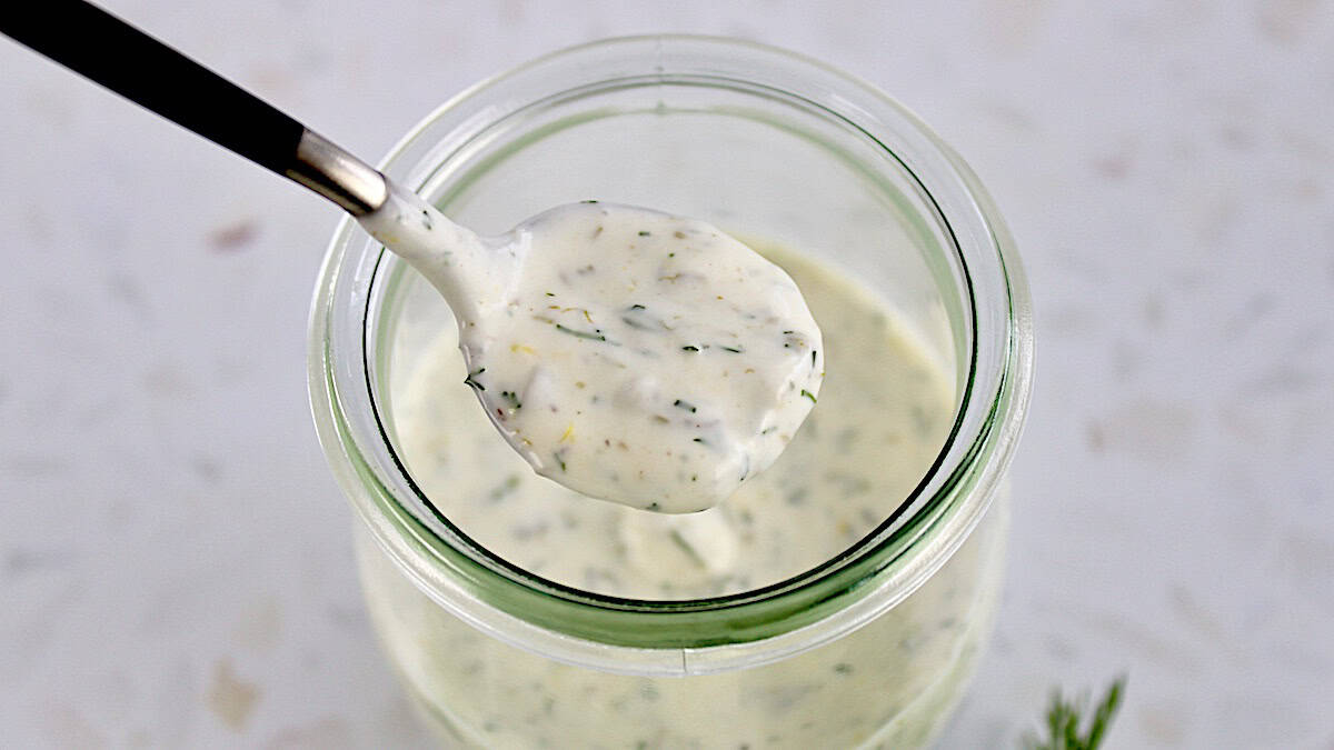 Creamy Dill Sauce being spooned out of open glass jar