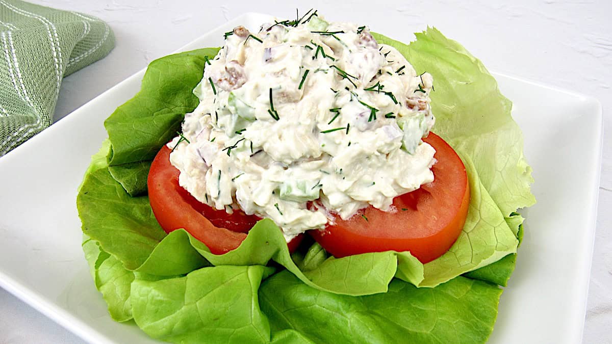 overhead view of scoop of chicken salad on tomatoes and lettuce