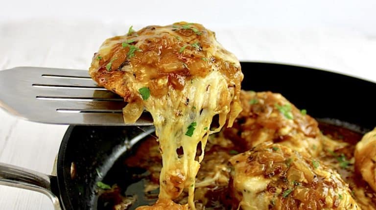 French Onion Chicken piece held up with spatula with cheese pulling