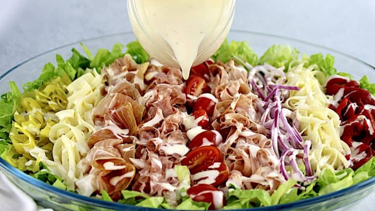 dressing being poured over grinder salad