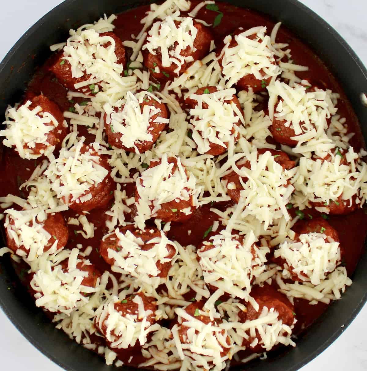 Keto Italian Meatballs in skillet with shredded mozzarella cheese on top