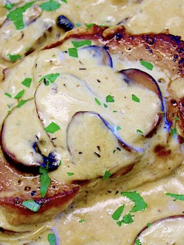 closeup of Keto Smothered Pork Chops in skillet with mushrooms and sauce on top