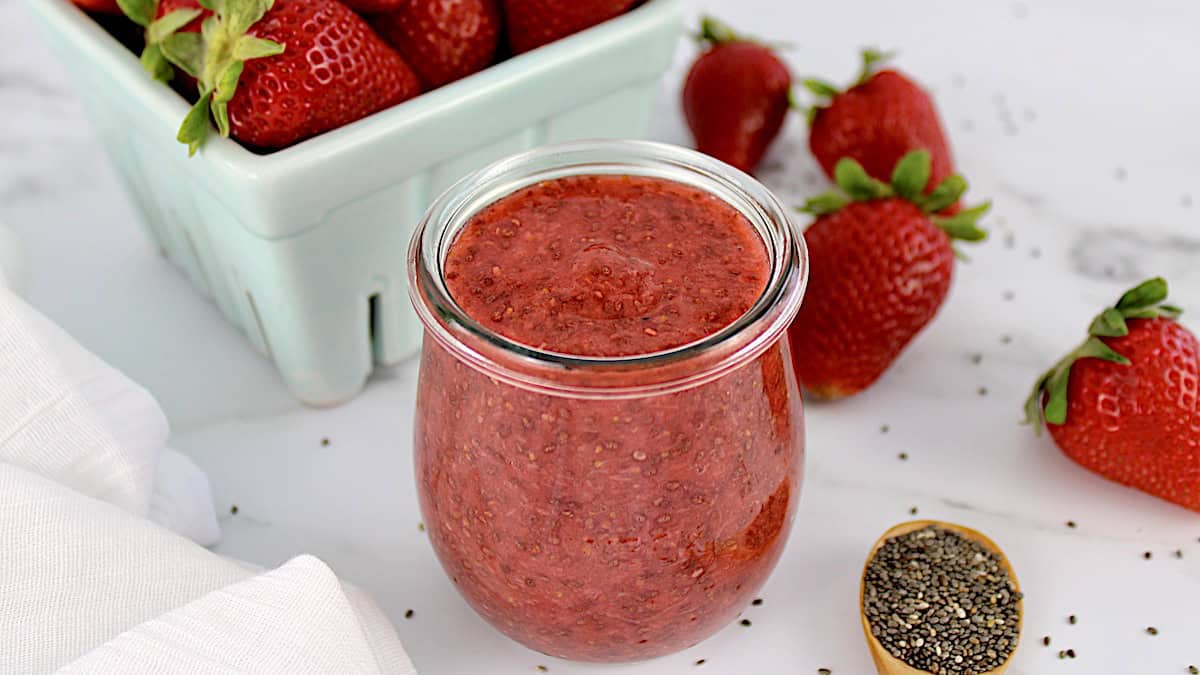 Keto Strawberry Chia Seed Jam in glass with strawberries in back