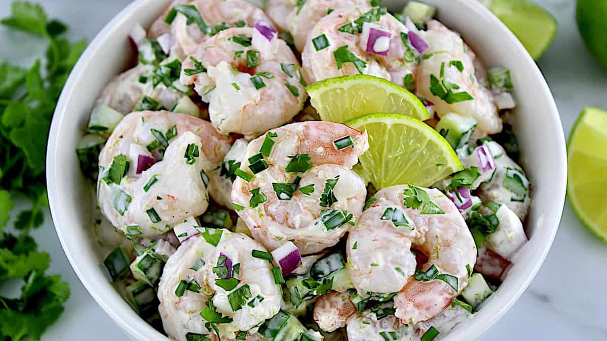 Lime Cilantro Shrimp Salad closeup in white bowl with 2 lime slices on top