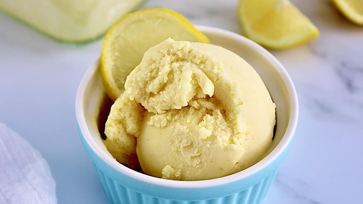 closeup of lemon curd ice cream in blue cup with lemon slice on top