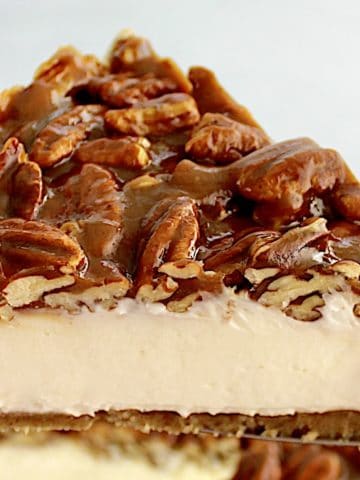 Pecan Pie Cheesecake slice held up with pie server