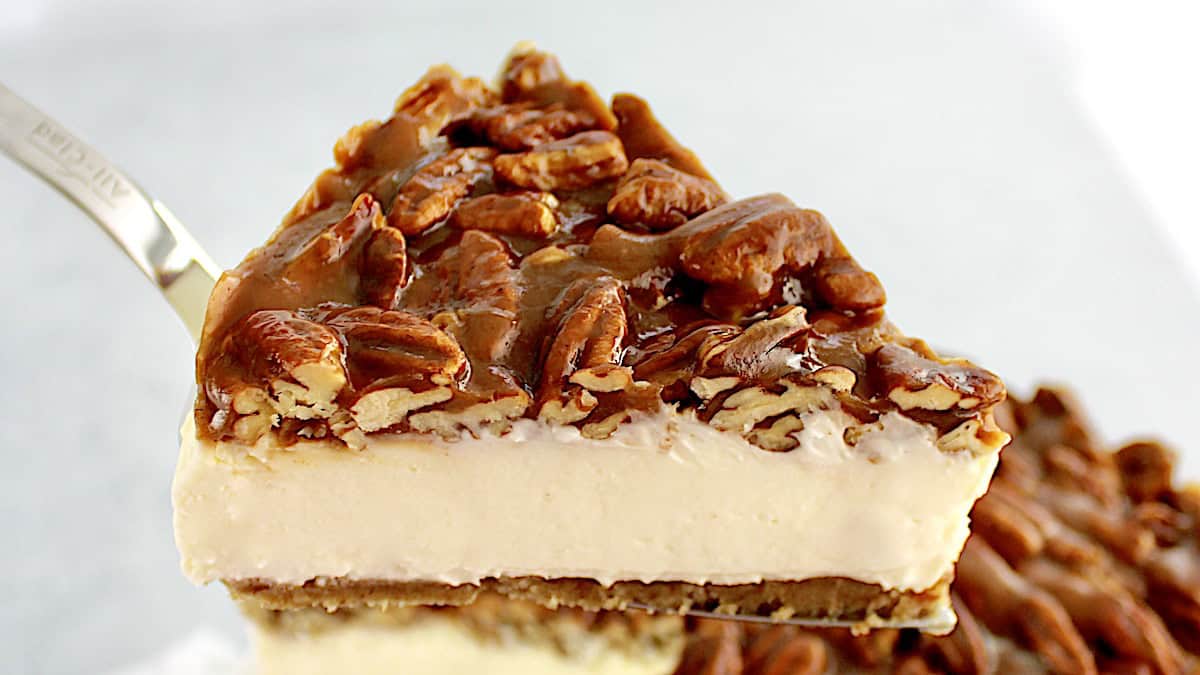 Pecan Pie Cheesecake slice held up with pie server