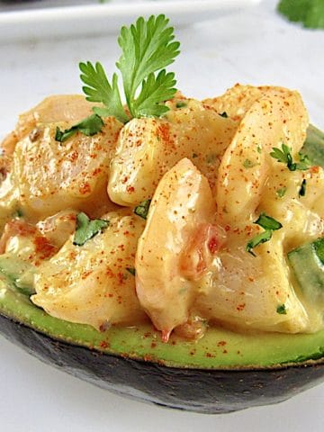 closeup shrimp salad in ½ avocado with cilantro in background