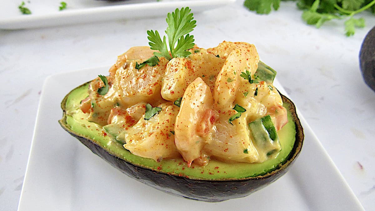 closeup shrimp salad in ½ avocado with cilantro in background