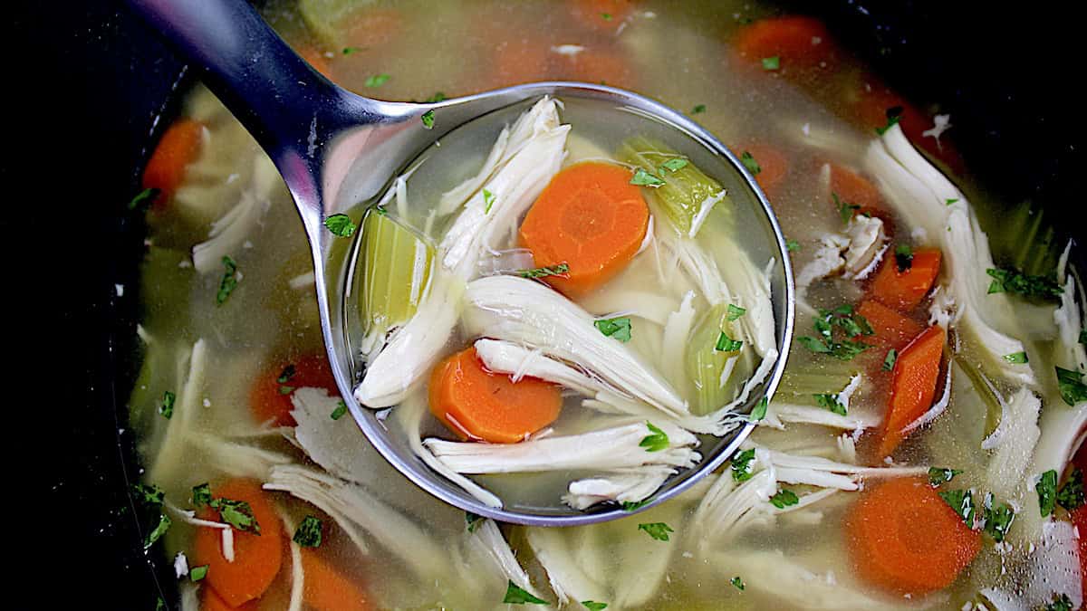 Slow Cooker Chicken Soup in silver ladle over crockpot