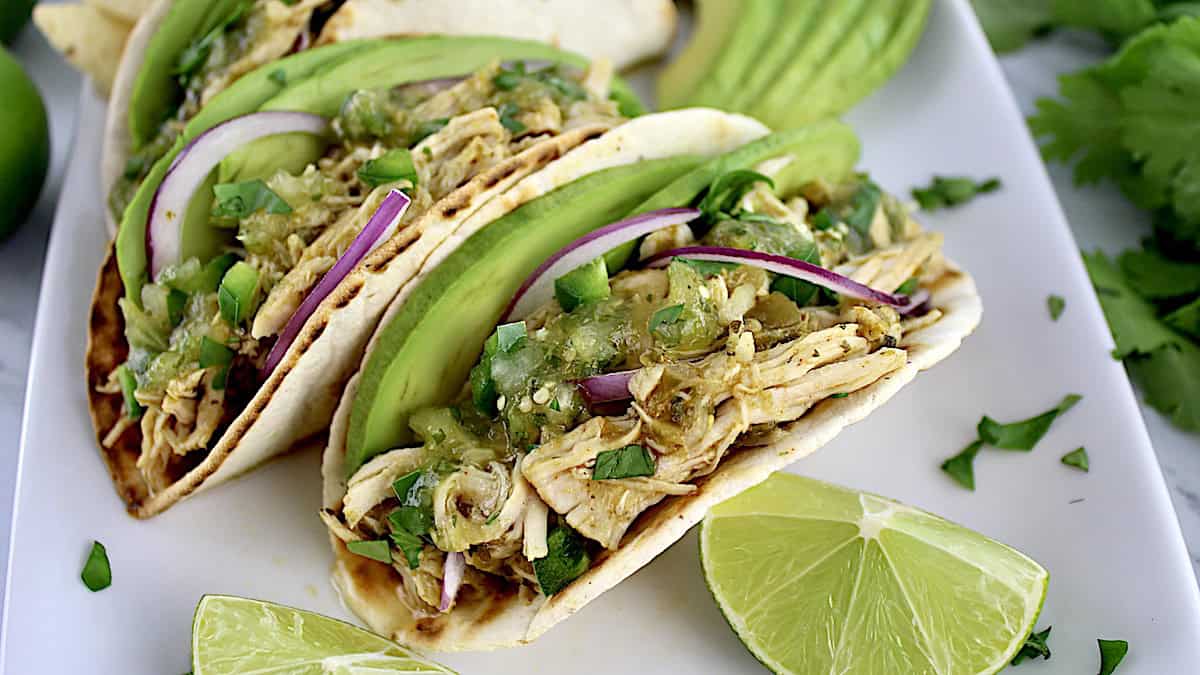 Slow Cooker Salsa Verde Chicken in tacos with avocado slices