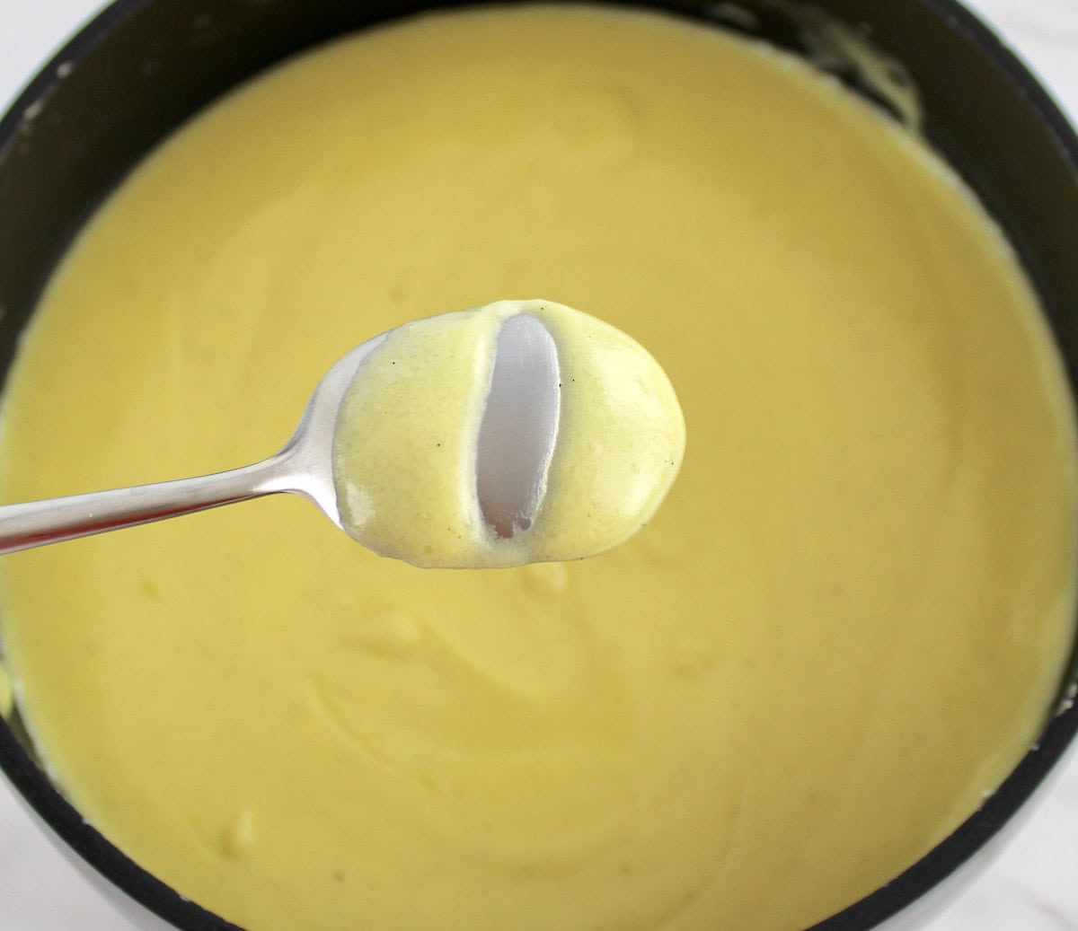 Sugar Free Keto Custard in saucepan and on back of silver spoon with line through it