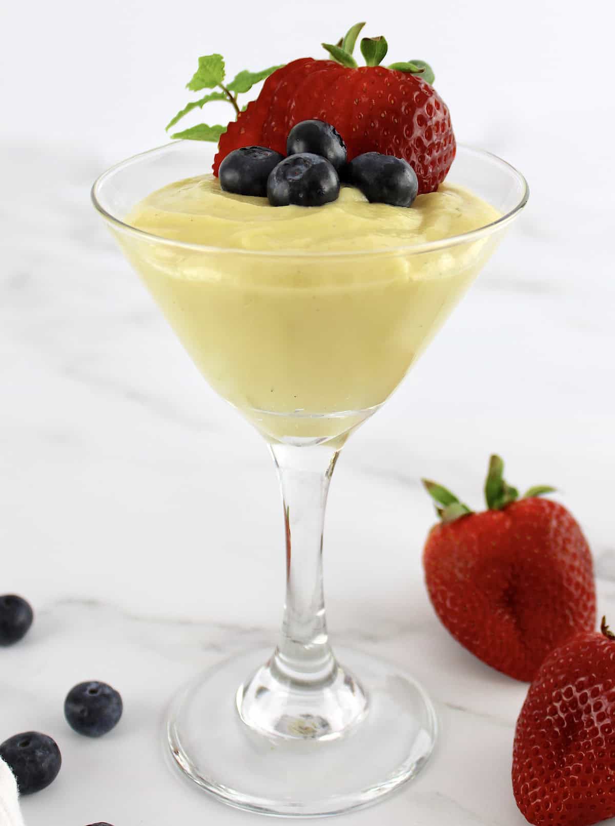 side view of Sugar Free Keto Custard in martini glass with strawberry and blueberries on top