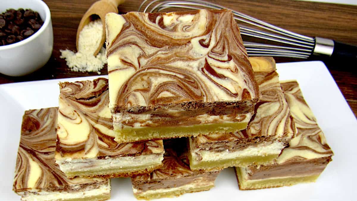 stack of vanilla chocolate swirl cheesecake bars on white plate