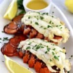 2 Air Fryer Lobster Tails on white oval plate with melted butter and lemon wedges