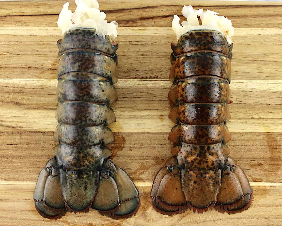 2 raw lobster tails on cutting board