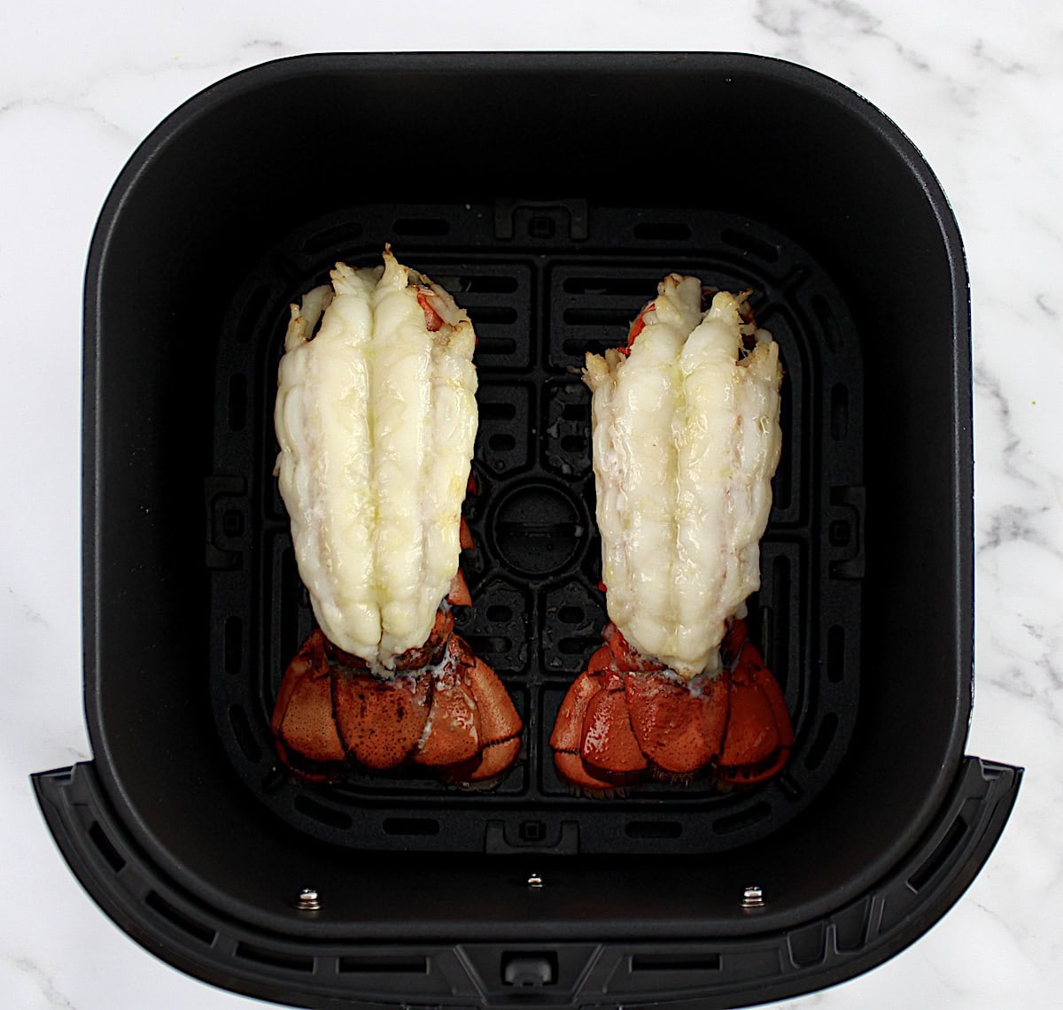 2 cooked Air Fryer Lobster Tails in air fryer basket