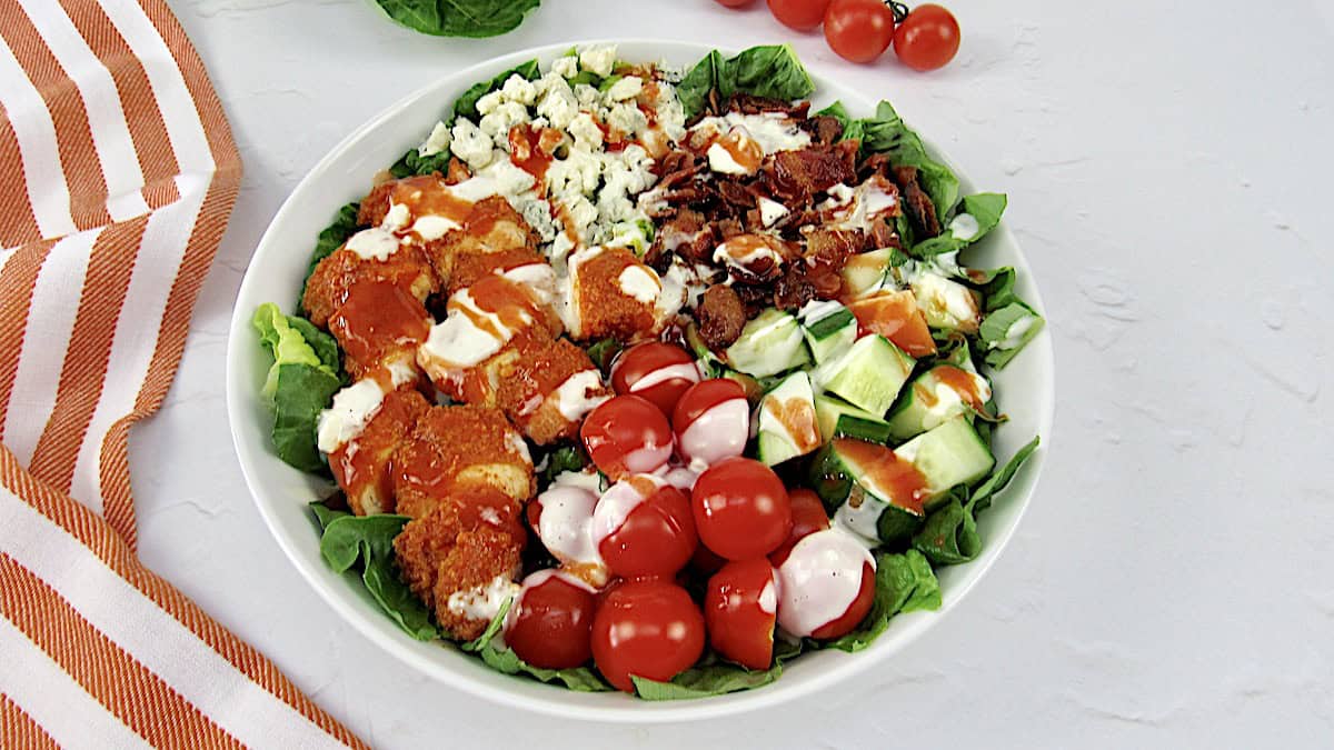 buffalo chicken salad with ingredients in sections and blue cheese dressing drizzled on top