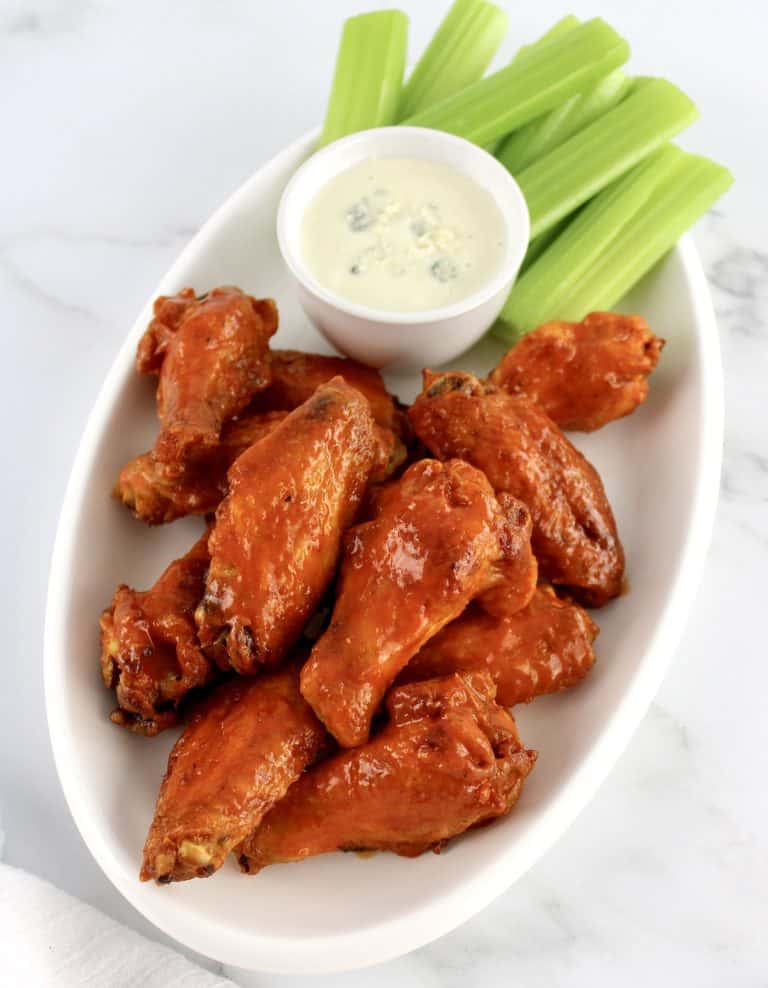 Crispy Air Fryer Buffalo Wings on white plate with bowl of blue cheese dressing and celery sticks