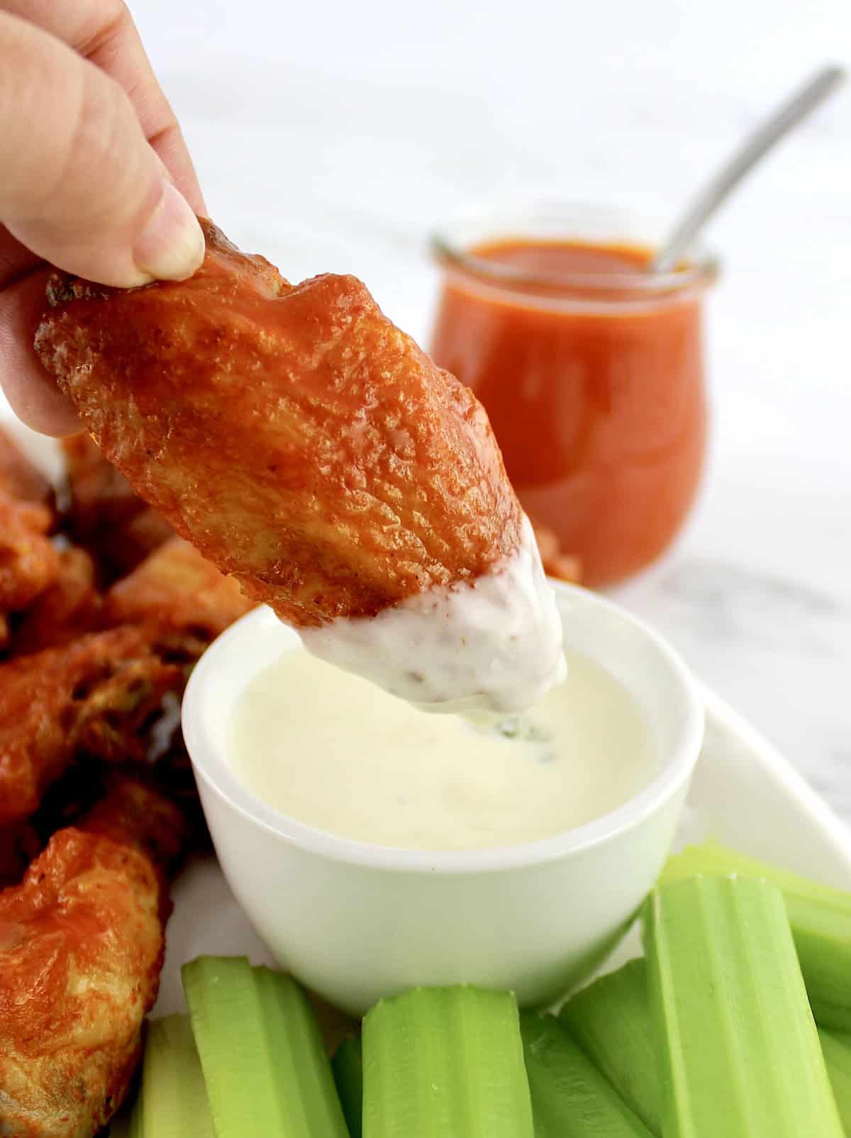 Crispy Air Fryer Buffalo Wing being dipped in blue cheese dressing in white cup