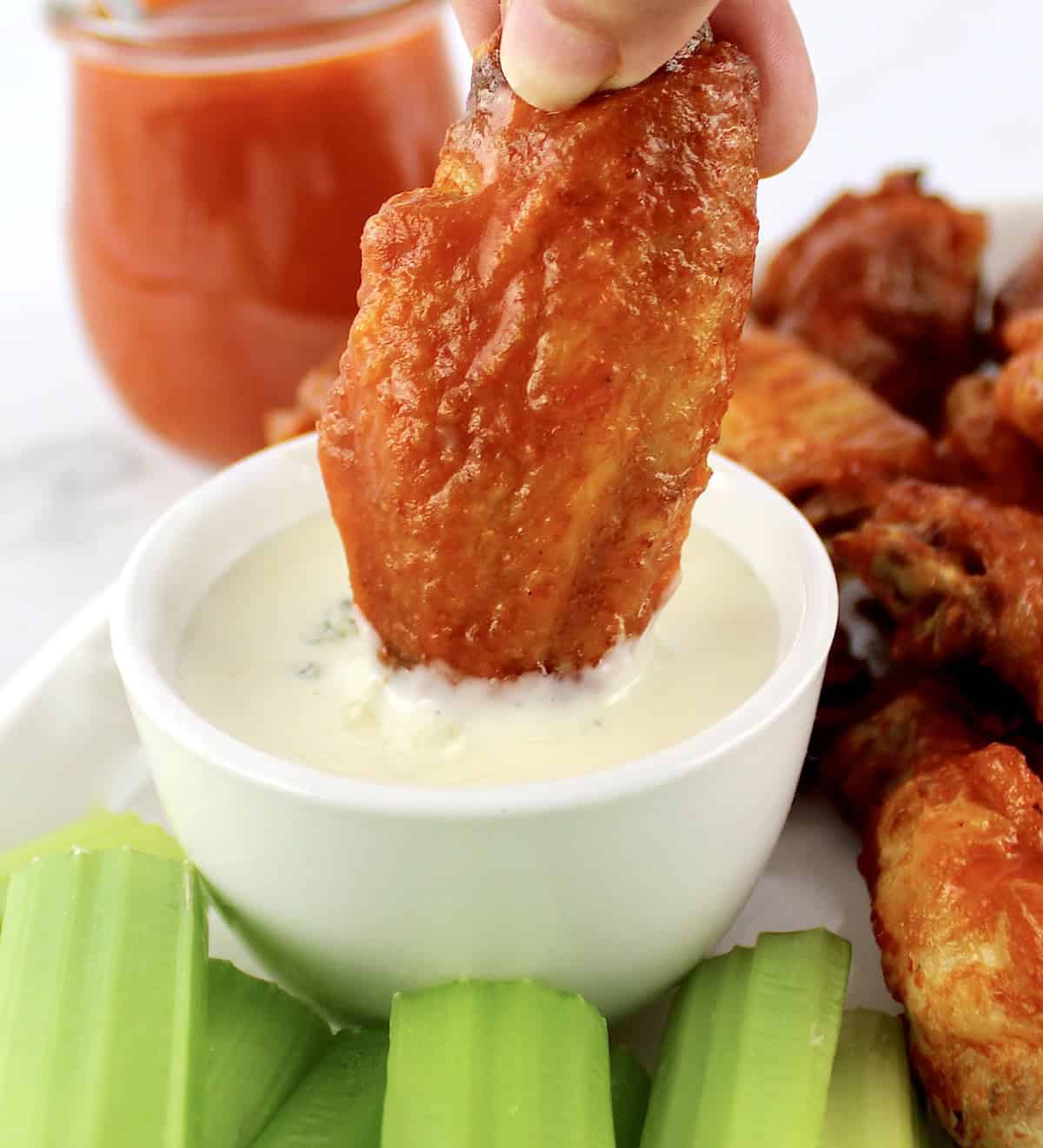 Crispy Air Fryer Buffalo Wing being dipped in blue cheese dressing in white cup