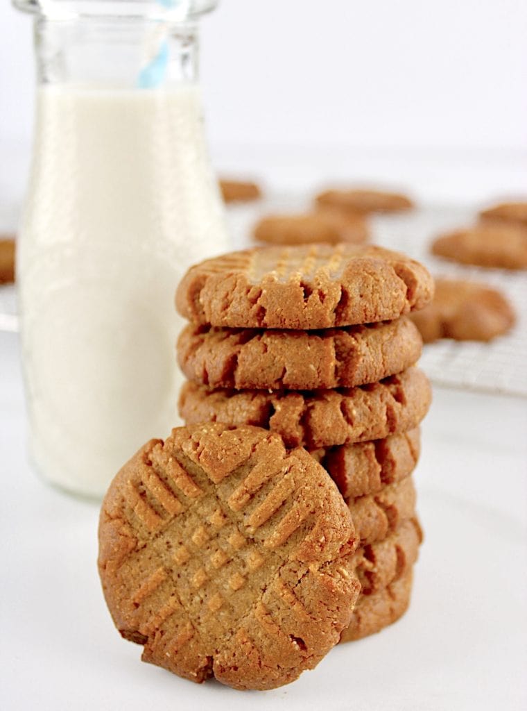 Easy Peanut Butter Cookies stacked up with one on side and milk bottle in back