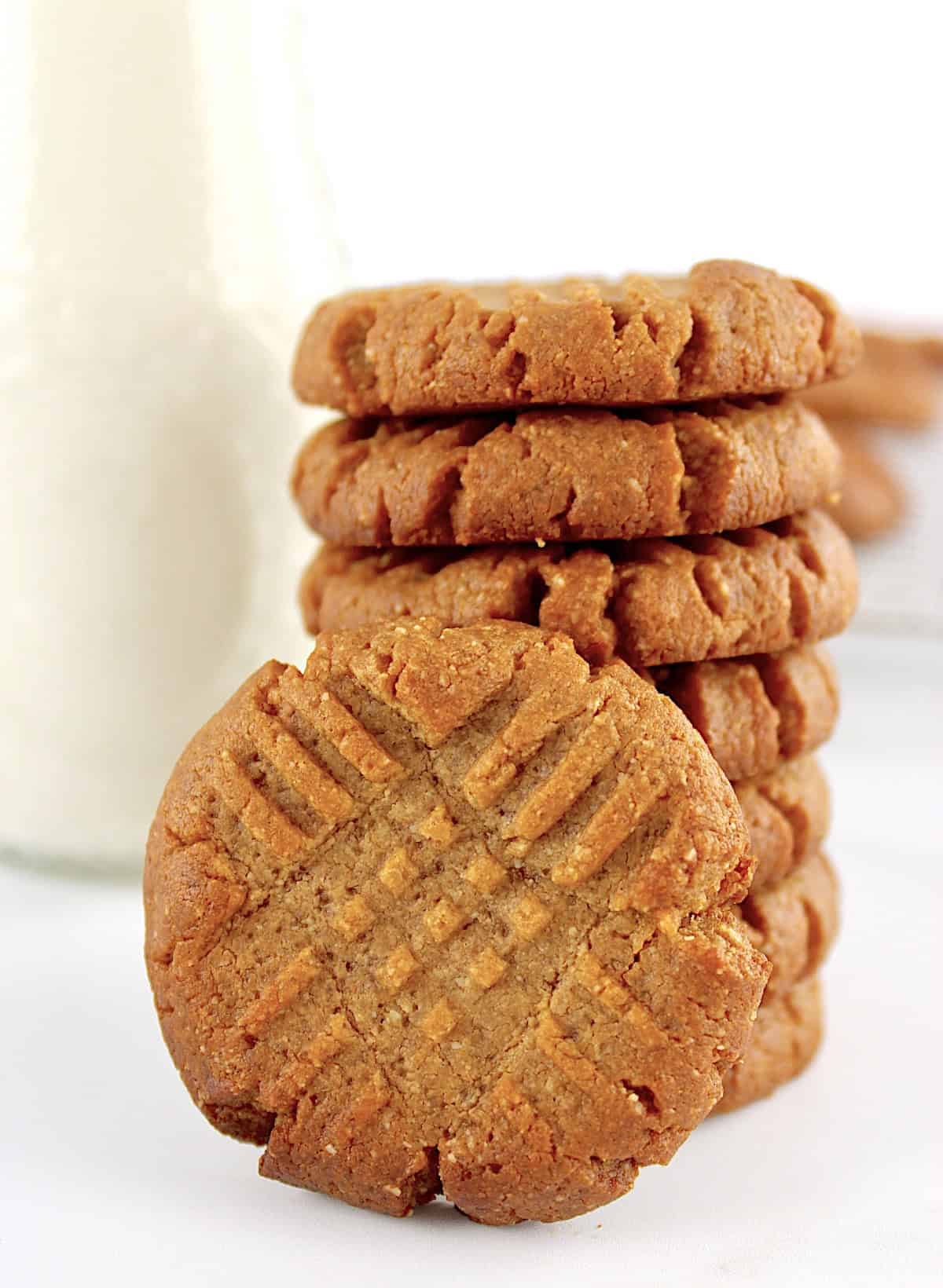 Easy Peanut Butter Cookies stacked up with one on side and milk bottle in back