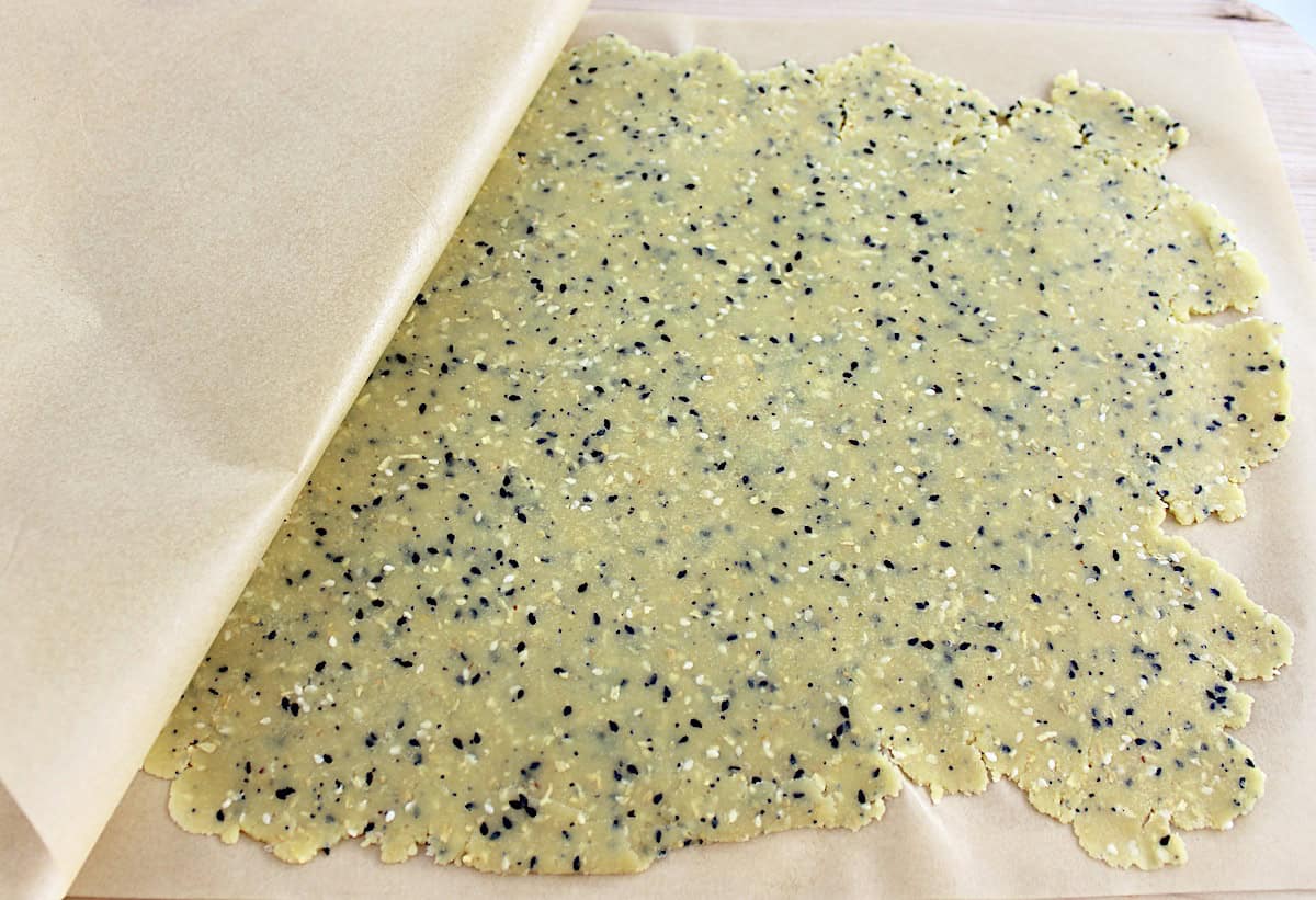 Everything Bagel Crackers dough on parchment paper rolled out thin
