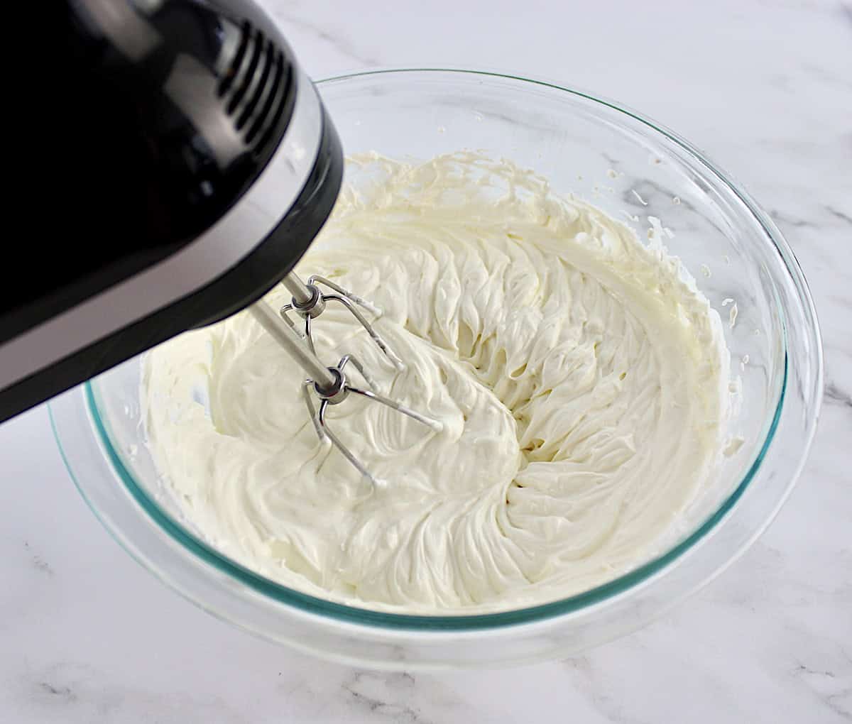 Everything Bagel Dip mix in glass bowl with hand mixer