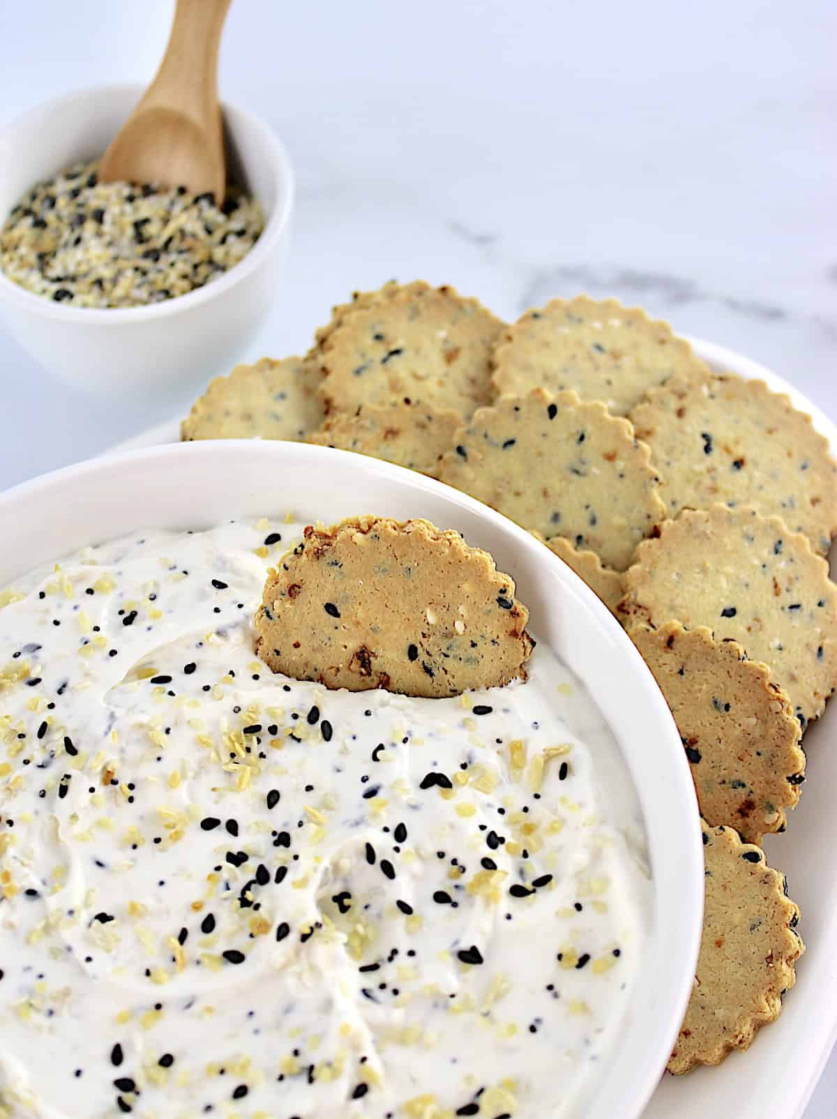 Everything Bagel Dip  in white bowl with cracker in the dip and more on the side