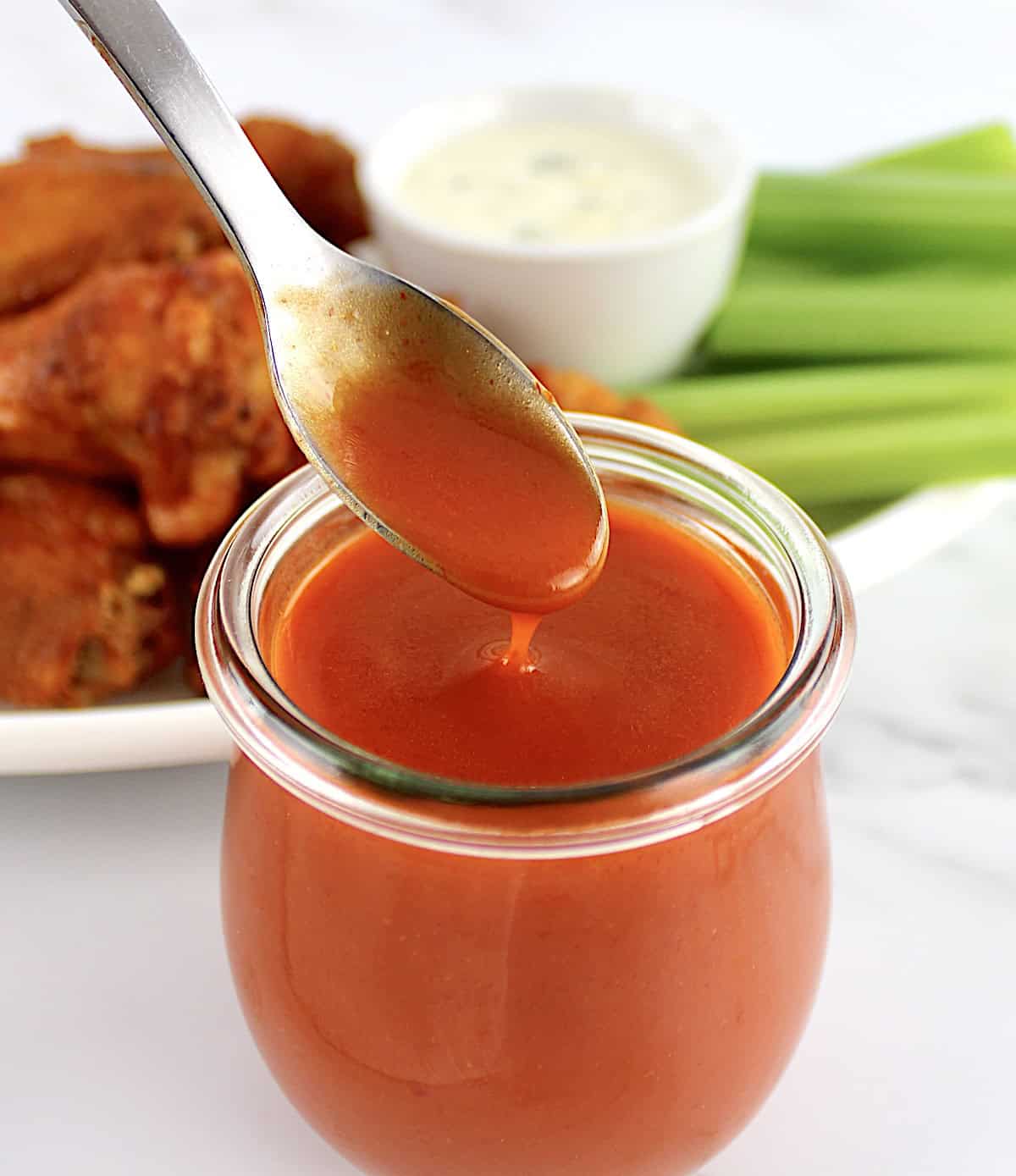 Homemade Buffalo Wing Sauce in open jar with spoon dripping