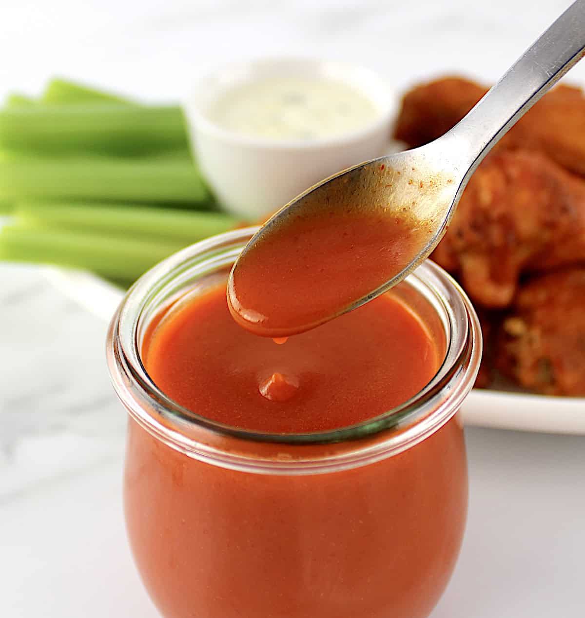 Homemade Buffalo Wing Sauce in open jar with spoon dripping