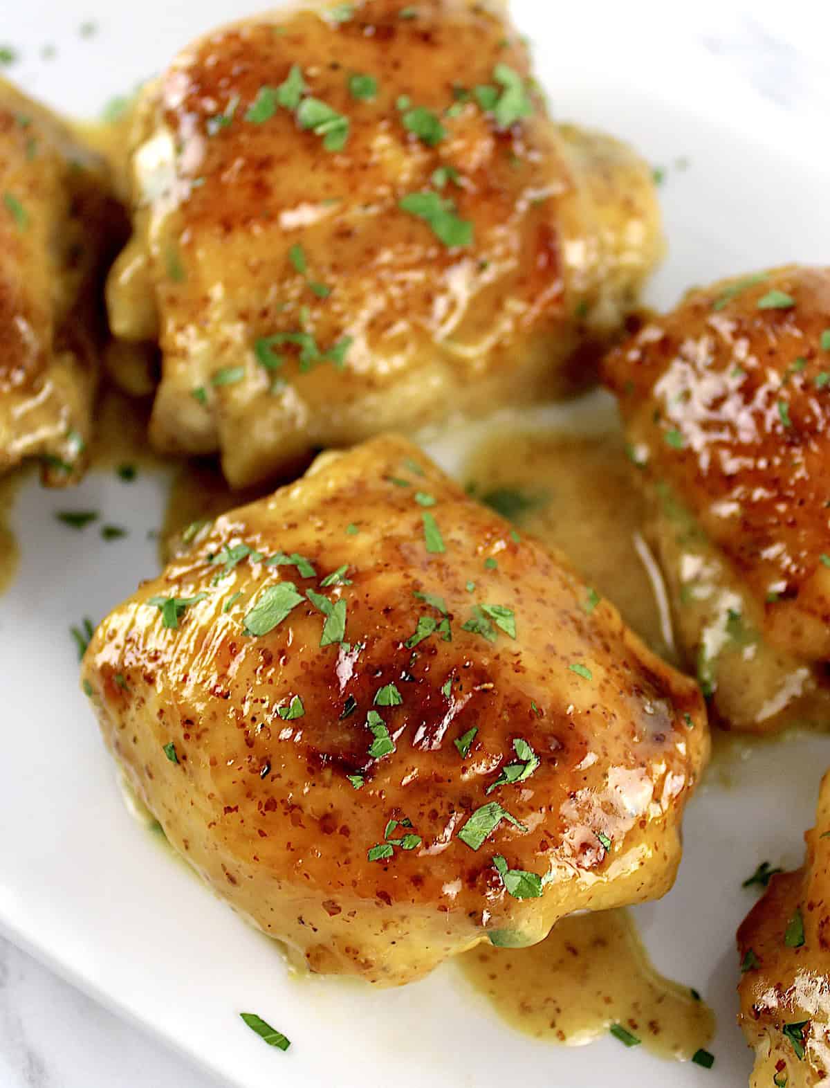 closeup of Honey Mustard Baked Chicken Thigh with chopped parsley on top