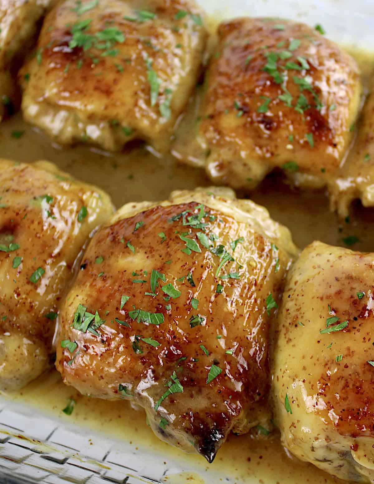 Honey Mustard Baked Chicken Thighs in glass casserole with parsley on top