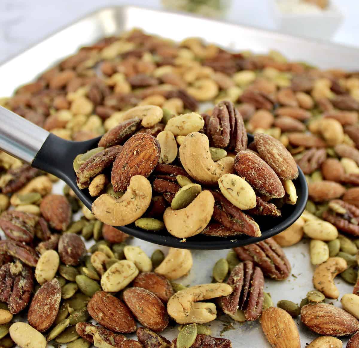 Ranch Roasted Nuts in black serving spoon over baking sheet