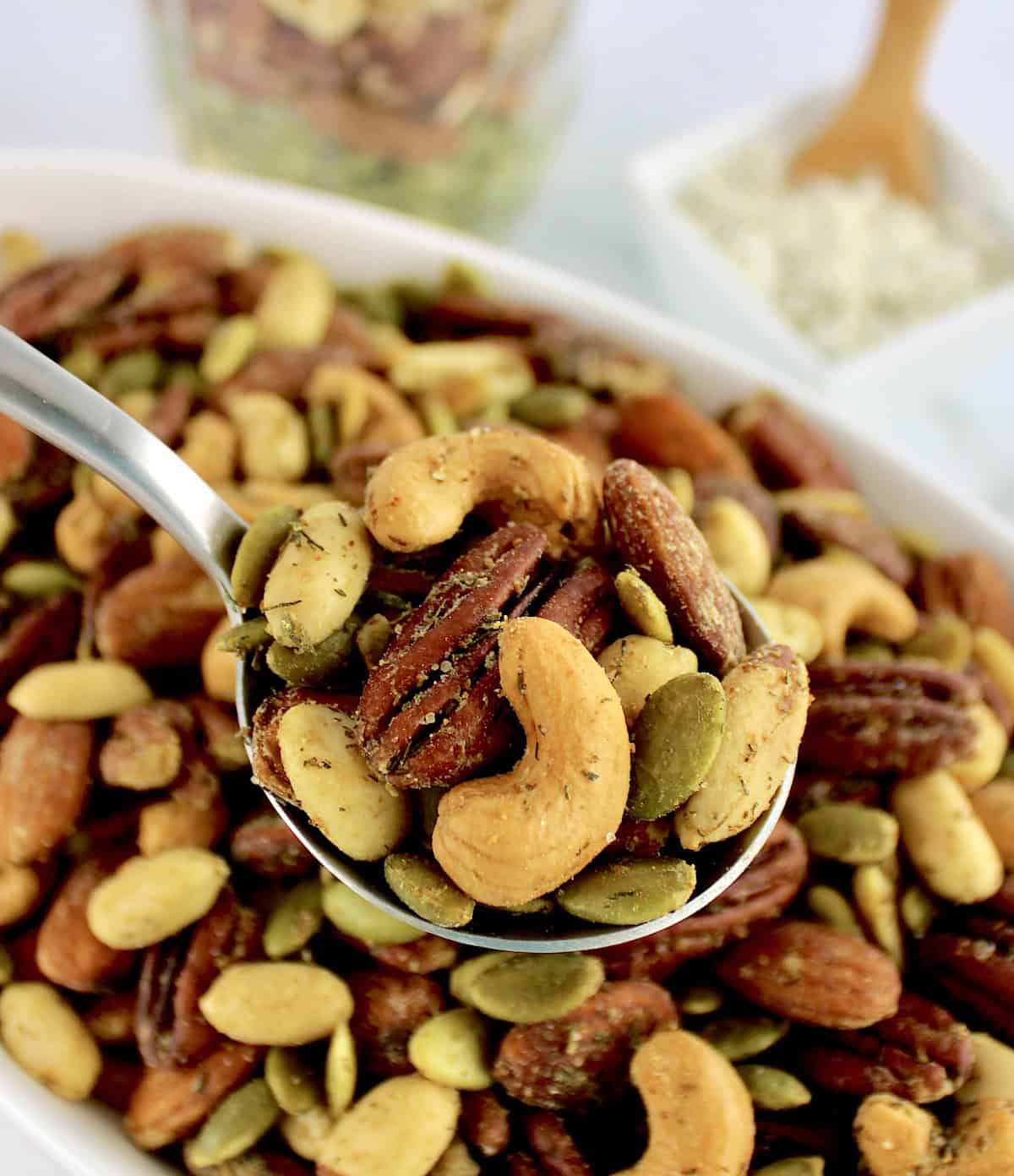 Ranch Roasted Nuts in spoon over more nuts in white bowl